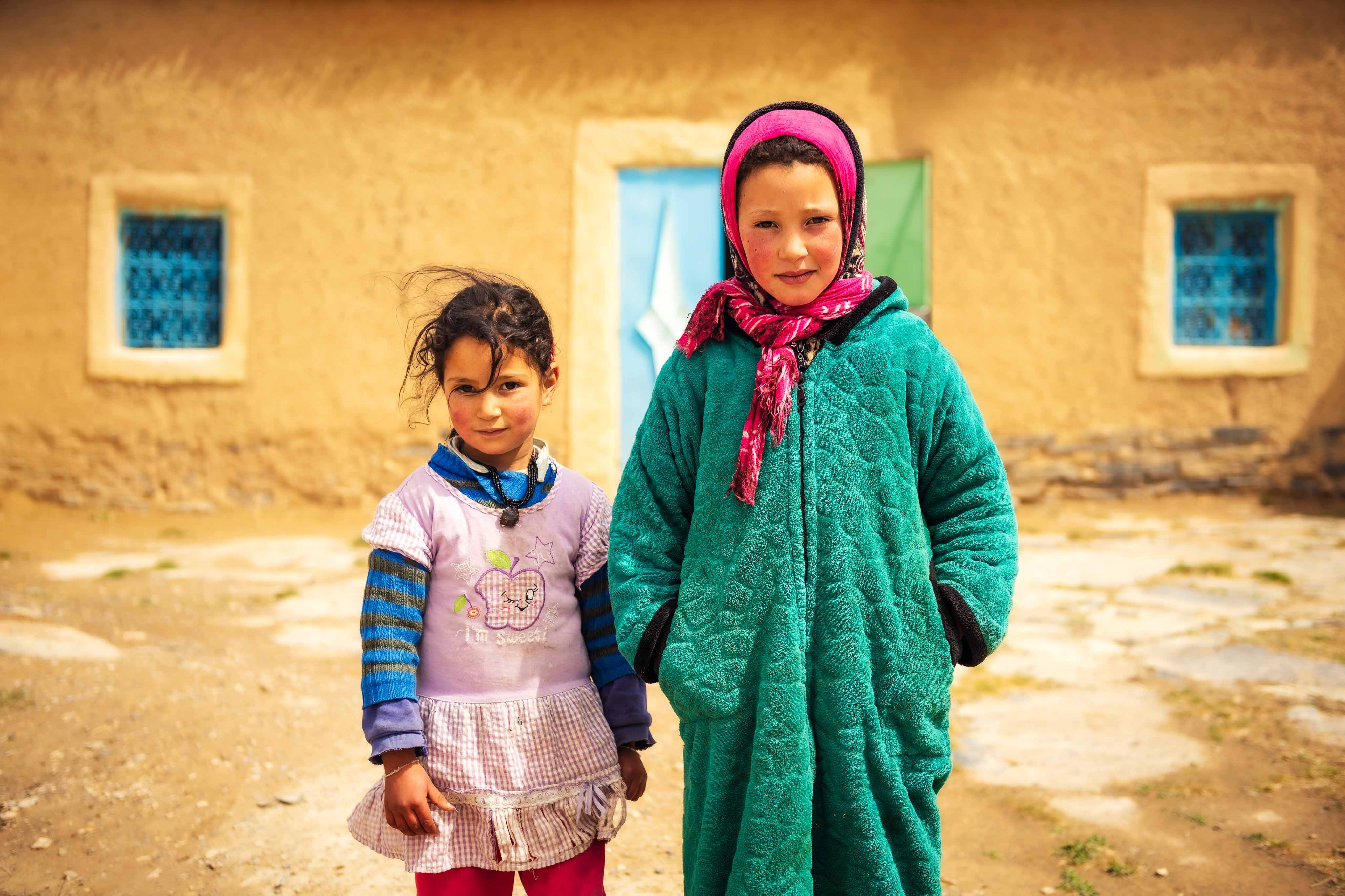 Zwei Mädchen (Geschwisterpaar) vor einem Berberhaus im Hohen Atlas in Marokko.